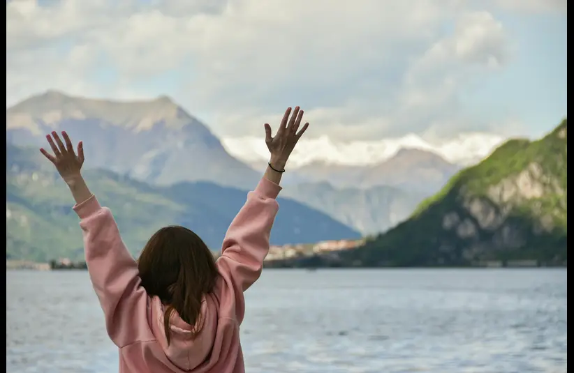 In daily devotional, a woman has her arms raised in praise.