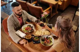 Couple enjoying a romantic dinner with wine at a cozy restaurant table showing casing one of budget dates
