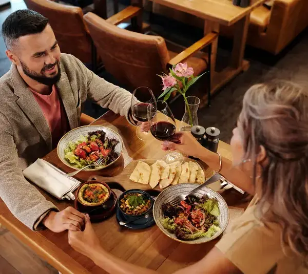 Couple enjoying a romantic dinner with wine at a cozy restaurant table showing casing one of budget dates
