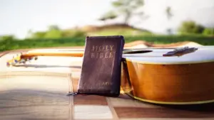 In daily devotional, an open Bible is shown by a guitar with an open field in the background
