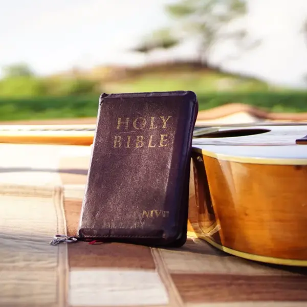 In daily devotional, an open Bible is shown by a guitar with an open field in the background