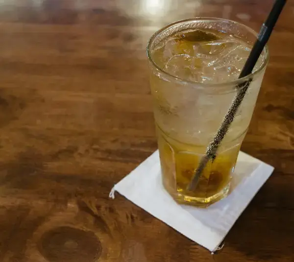 Glass of dirty soda with ice cubes on a wooden table, capturing a refreshing moment