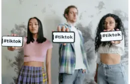 Group of young adults holding phones with #tiktok indoors, showcasing social media culture. -travel destinations