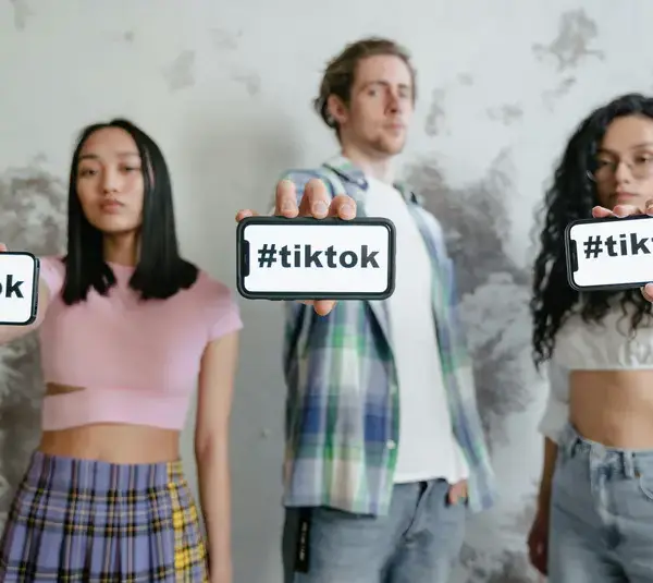 Group of young adults holding phones with #tiktok indoors, showcasing social media culture. -travel destinations