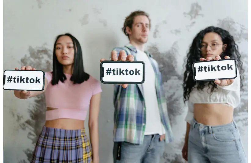 Group of young adults holding phones with #tiktok indoors, showcasing social media culture. -travel destinations