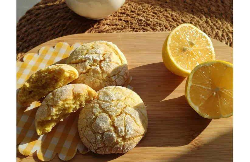 Image of a cut lemon and lemon cookies on a wood tray