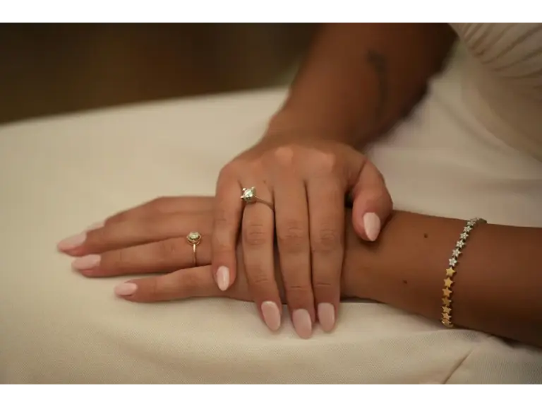 A close-up photo showcasing elegant manicured natural nails adorned with rings and a bracelet