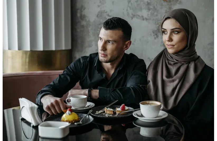 A stylish couple enjoys coffee and dessert in a modern café setting, highlighting cultural elegance and the effortless charm of dessert dates.