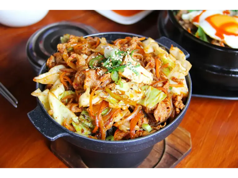 Savory Korean stir‑fried noodles with vegetables and meat in a traditional stone bowl, perfect for enjoying during this flavorful cabbage comeback.