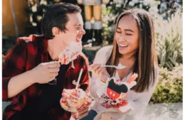 Smiling couple enjoying festive desserts outdoors during cozy dessert dates, sharing a joyful and relaxed moment together.