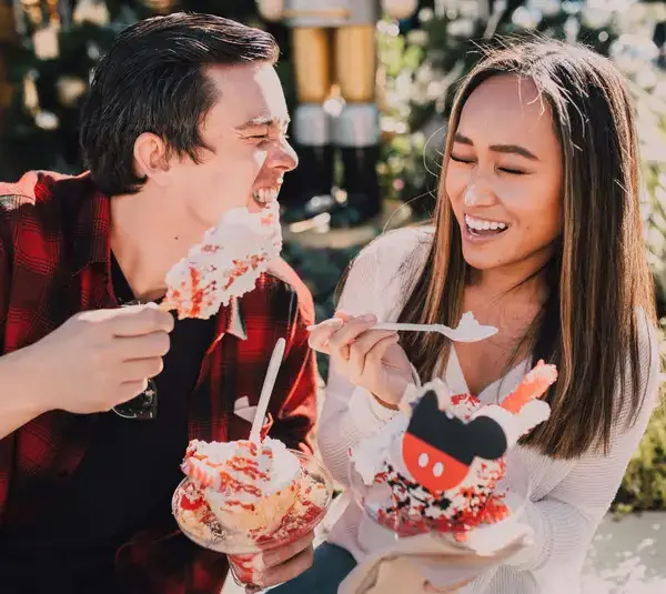 Smiling couple enjoying festive desserts outdoors during cozy dessert dates, sharing a joyful and relaxed moment together.