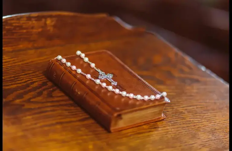 In daily devotional , a Bible is draped with a pearl necklace with a cross pendant.