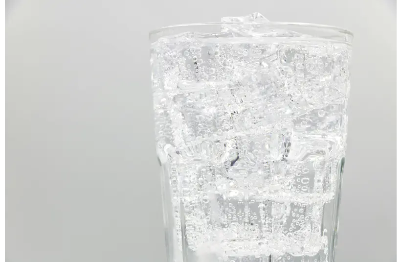 Close-up of a glass filled with sparkling water and ice cubes, ideal for refreshing summer drinks