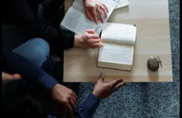 In daily devotional, two people are show sitting and studying the Bible together.