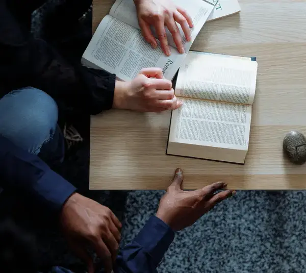 In daily devotional, two people are show sitting and studying the Bible together.