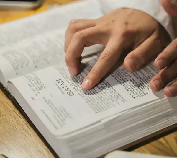 In daily devotional, a man is reading the Bible using his fingers to follow along.
