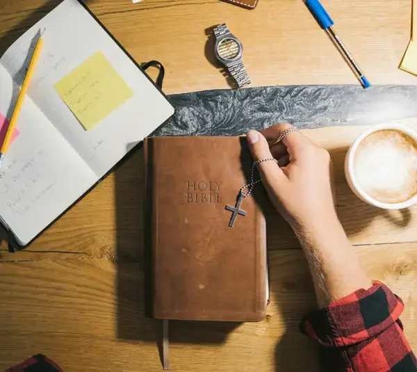 In the daily devotional, a person gets ready to do Bible study with Bible and notebook on table.