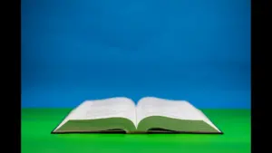 In daily devotional, an open Bible in seen with a colorful background of blue and green.
