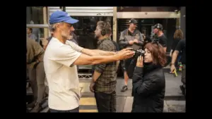 Taika Waititi blocking Jenna Ortega from looking through a camera lens.