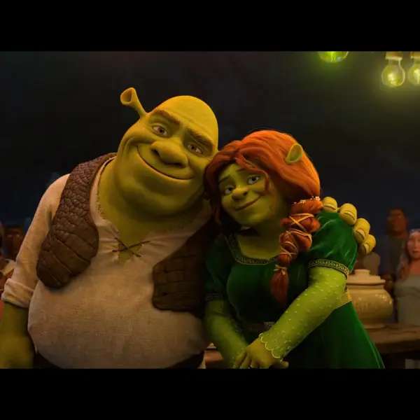 Shrek and Fiona from the animated movie "Shrek" embrace happily while another character, likely Shrek's friend, stands nearby, with a group of people in the background in Shrek 5