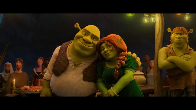 Shrek and Fiona from the animated movie "Shrek" embrace happily while another character, likely Shrek's friend, stands nearby, with a group of people in the background in Shrek 5