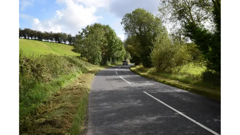 A quiet rural mystery road at Magnetic Hill in Cullion gently slopes through open countryside, creating the eerie optical illusion of cars rolling uphill.