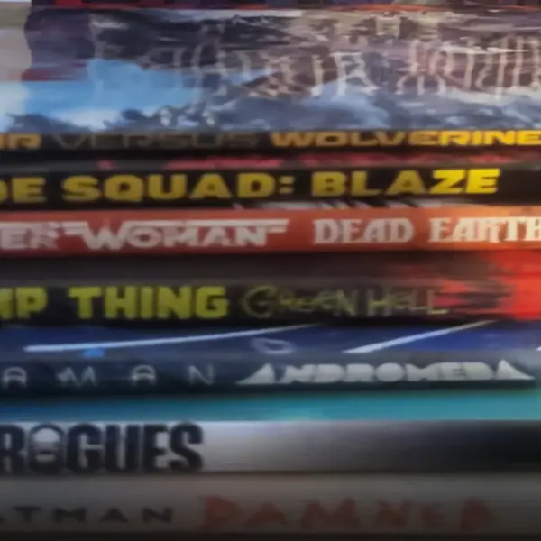 A stack of various comic books and graphic novels, including a prominent DC Black Label Batman book on top.