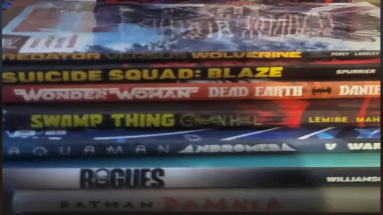 A stack of various comic books and graphic novels, including a prominent DC Black Label Batman book on top.