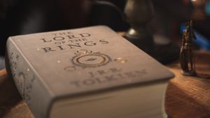 A cozy candlelit setting featuring 'The Lord of the Rings' book on a wooden surface.