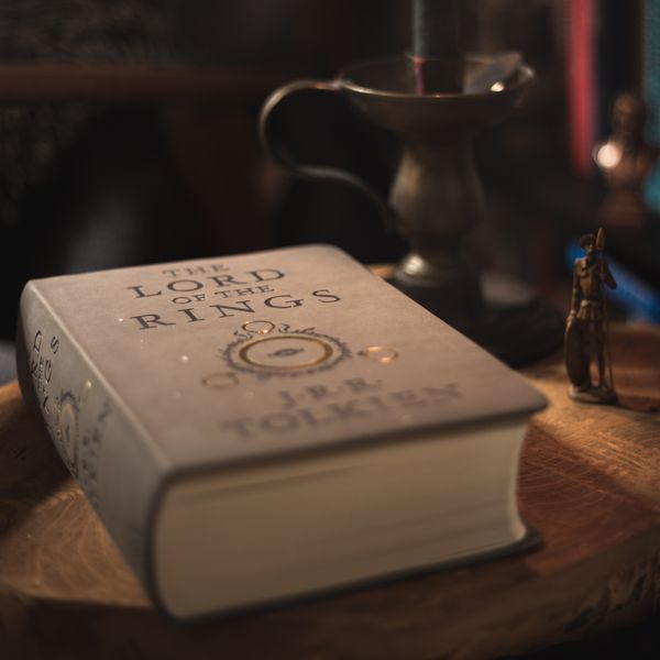 A cozy candlelit setting featuring 'The Lord of the Rings' book on a wooden surface.