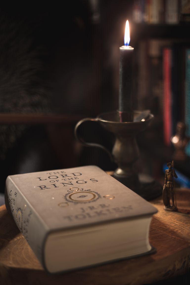 A cozy candlelit setting featuring 'The Lord of the Rings' book on a wooden surface.
