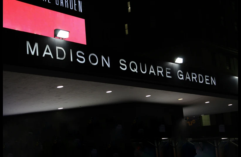 Nighttime image of the Madison Square Garden entrance with illuminated signage against a dark sky, exuding an energetic and iconic urban vibe. Possible venue for Taylor Swift's wedding.