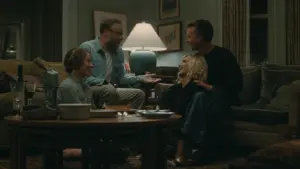 The cast of A24's "The Invite" are seated at a table in a living room, sharing ideas and enjoying each other's company.