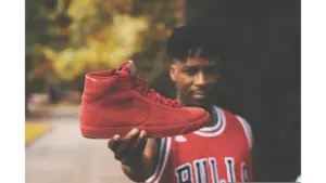 adult in basketball streetwear, holding Air Jordan shoes