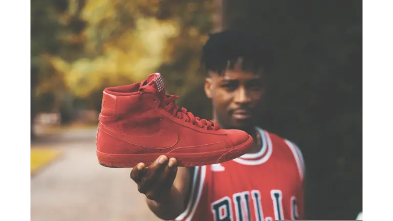 adult in basketball streetwear, holding Air Jordan shoes