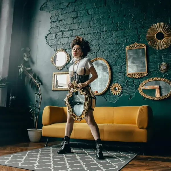 Statement mirrors frame a fashionable woman posing with a mirror in a chic room, reflecting contemporary style with bold, modern flair