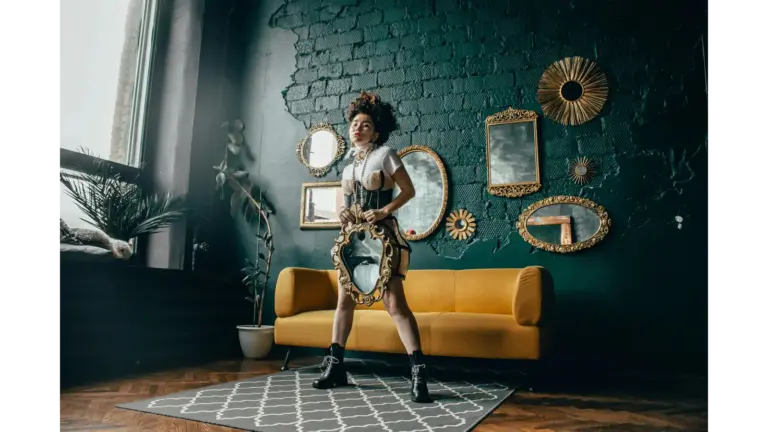 Statement mirrors frame a fashionable woman posing with a mirror in a chic room, reflecting contemporary style with bold, modern flair
