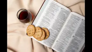 In daily devotional, an open Bible has communion elements on and beside it.