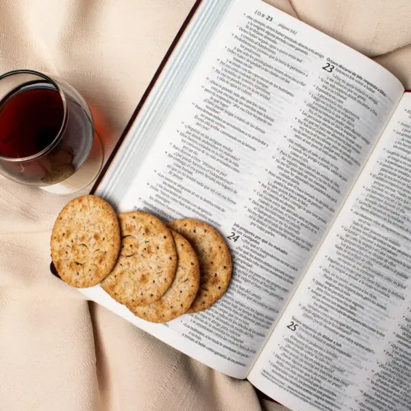 In daily devotional, an open Bible has communion elements on and beside it.