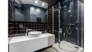 Bathroom tiles elevate this stylish bathroom with black tile walls, a glass shower, and sleek modern fixtures