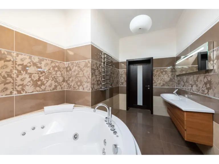 Bathroom tiles set the vibe in a spacious modern bathroom featuring a Jacuzzi, floral tile decor, and a warm wooden vanity.