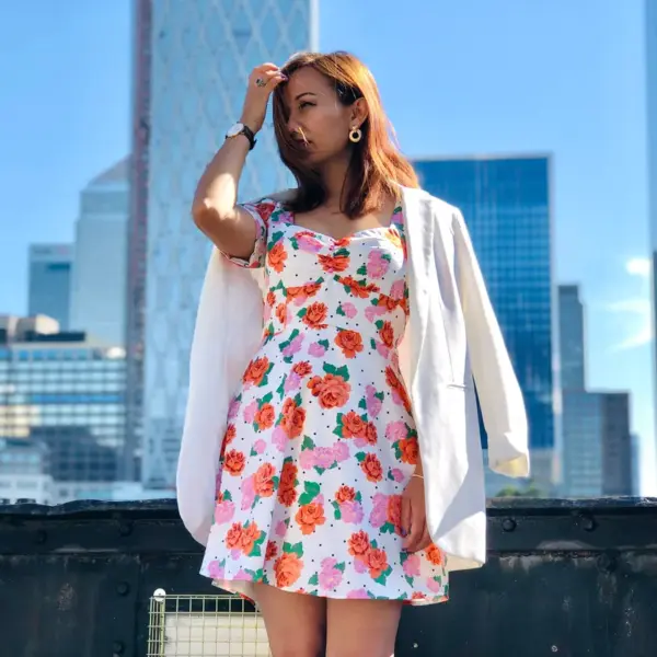 A fashionably dressed woman in a floral dress poses against a London city backdrop, highlighting the timeless appeal of floral dresses.