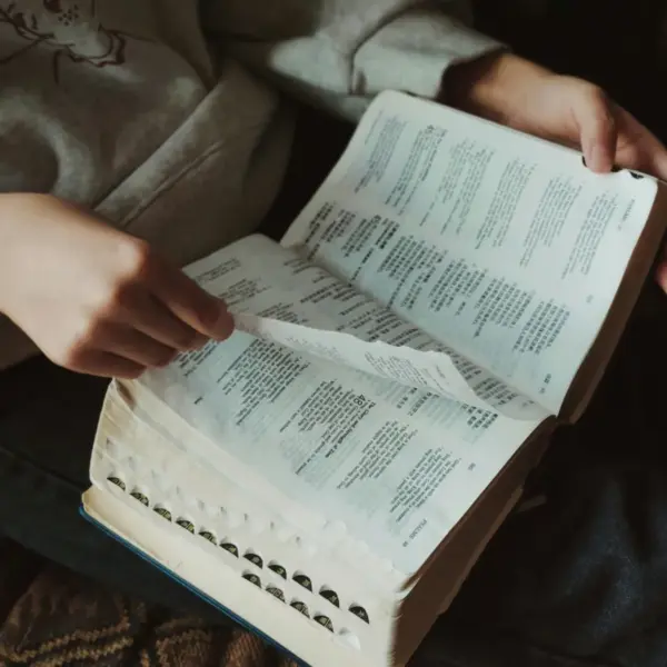 In daily devotional, a person is reading the Bible in a dark background.