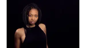 a stunning portrait of a Black woman with braided hair, exuding confidence against a dark background, beautifully highlighting the bold, structured look of bob braids.
