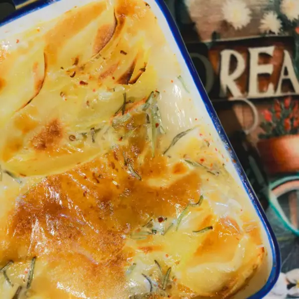 rich and creamy potatoes freshly baked, golden and crispy in a ceramic dish.
