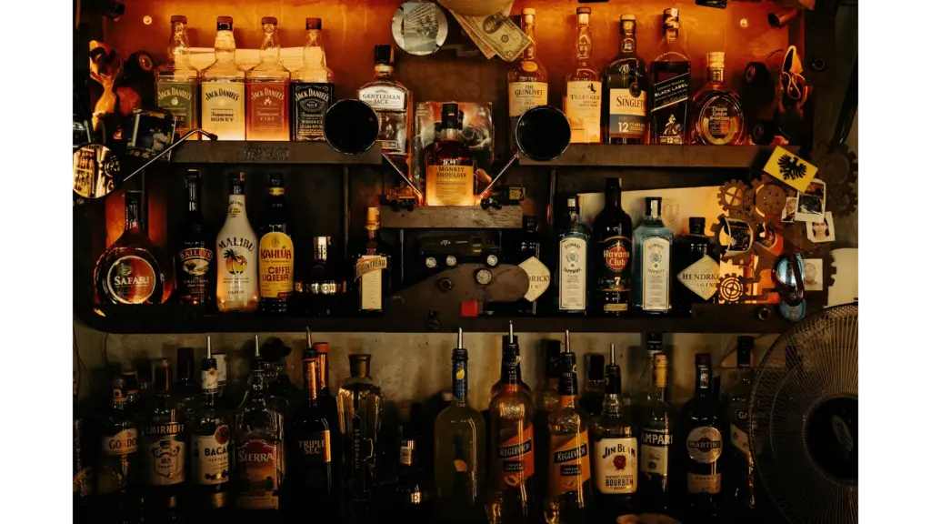 An indoor bar with an eclectic display of various vintage liquor bottles on shelves, creating a warm ambiance