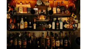 An indoor bar with an eclectic display of various vintage liquor bottles on shelves, creating a warm ambiance