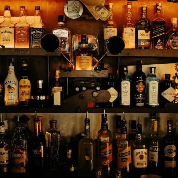 An indoor bar with an eclectic display of various vintage liquor bottles on shelves, creating a warm ambiance