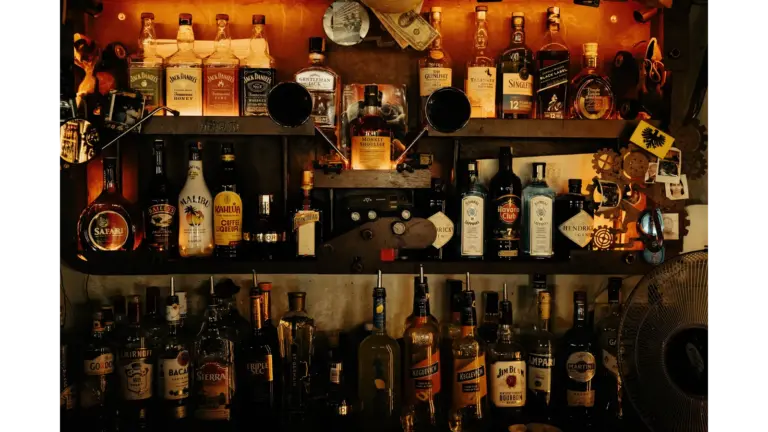 An indoor bar with an eclectic display of various vintage liquor bottles on shelves, creating a warm ambiance