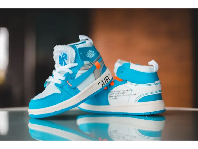 Close-up of vibrant blue kids' jordans on a glossy surface indoors.